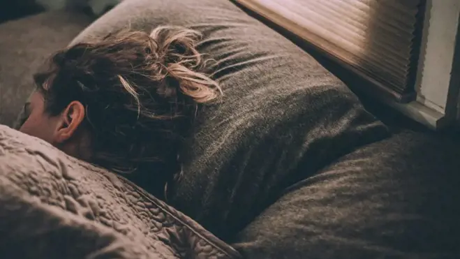 Eine Person, die im Bett schläft und veranschaulicht, wie guter Schlaf die Spermiengesundheit unterstützt und ihre Überlebensfähigkeit verbessert