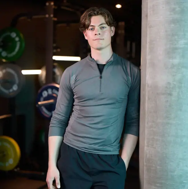 Ein Mann, der selbstbewusst in einem Fitnessstudio posiert und seine Fitness als Samenspender hervorhebt.