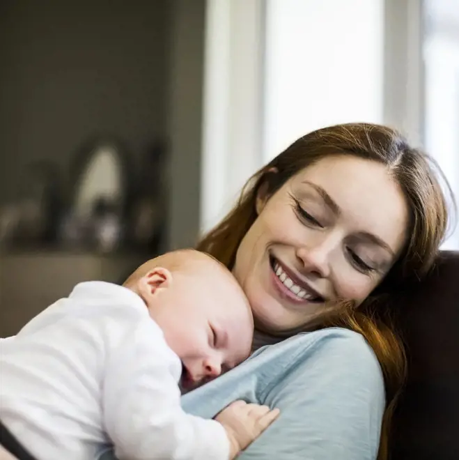 A woman smiles while holding her baby, celebrating her journey as a single mother by choice.
