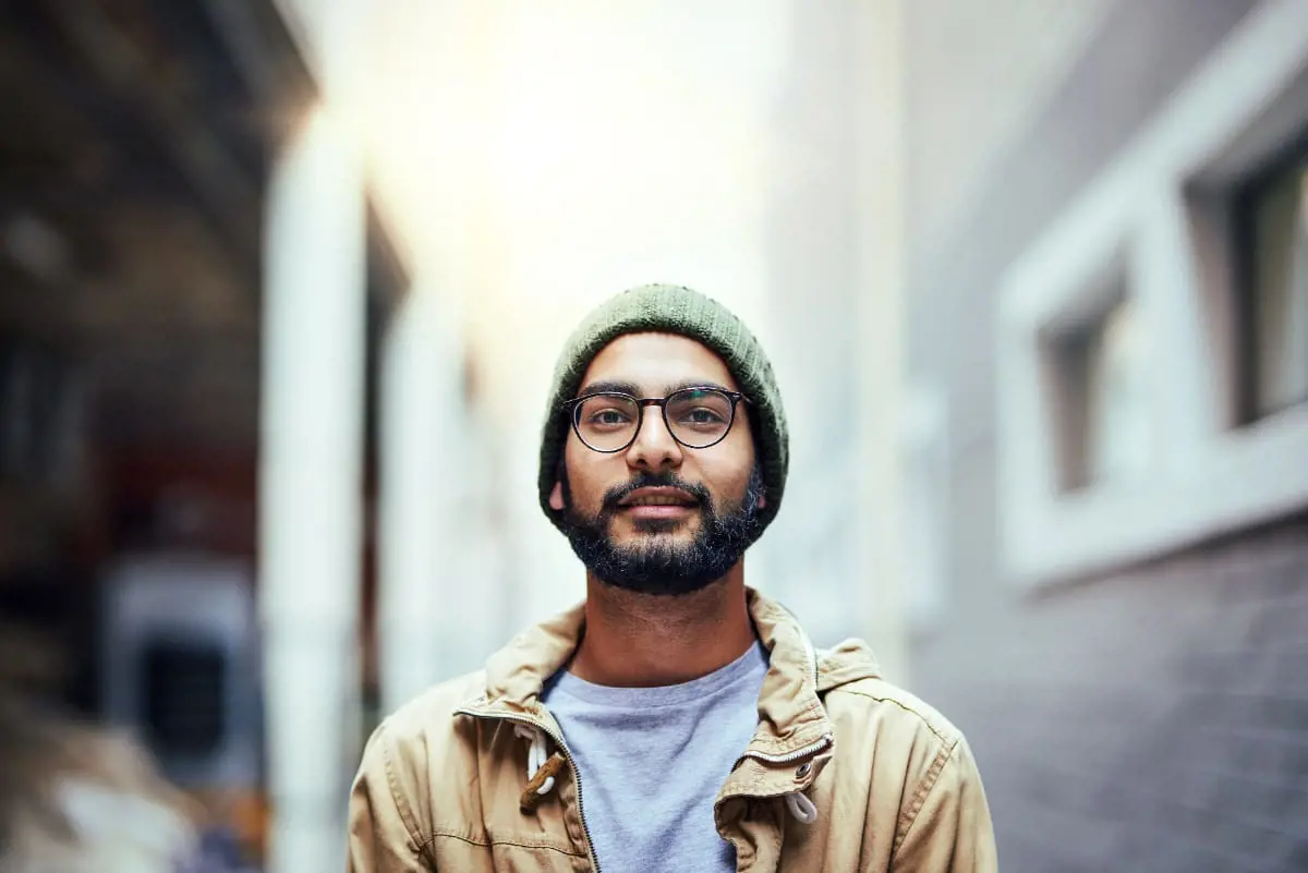 Young man with glasses and a beard poses on an urban street, noted for his role as a sperm donor