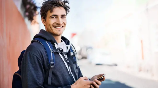 Ein Samenspender mit Rucksack hält sein Mobiltelefon in der Hand