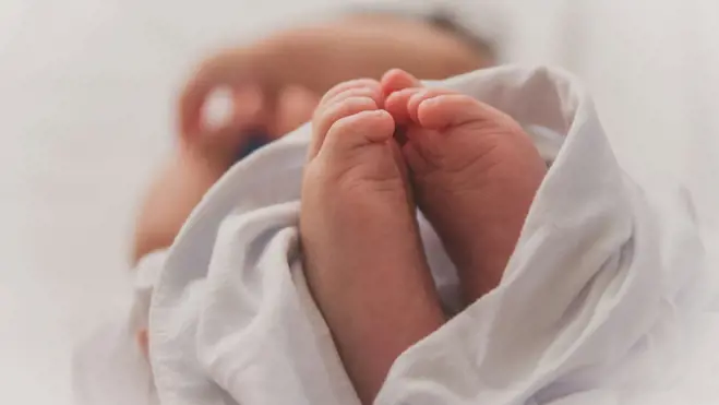 Newborn baby's feet wrapped in white cloth, symbolizing a donor-conceived child.