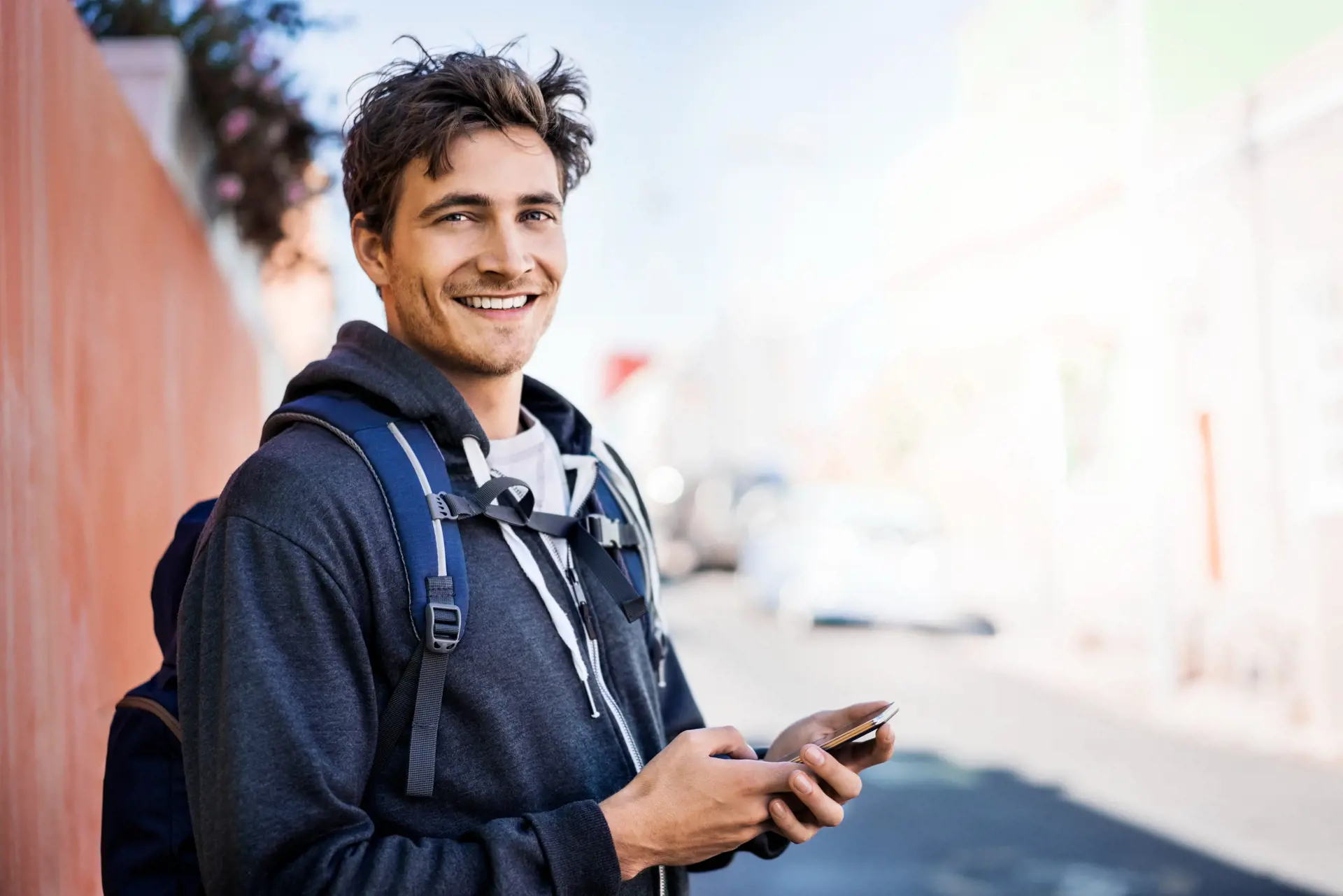 A sperm donor with a backpack holds his cell phone